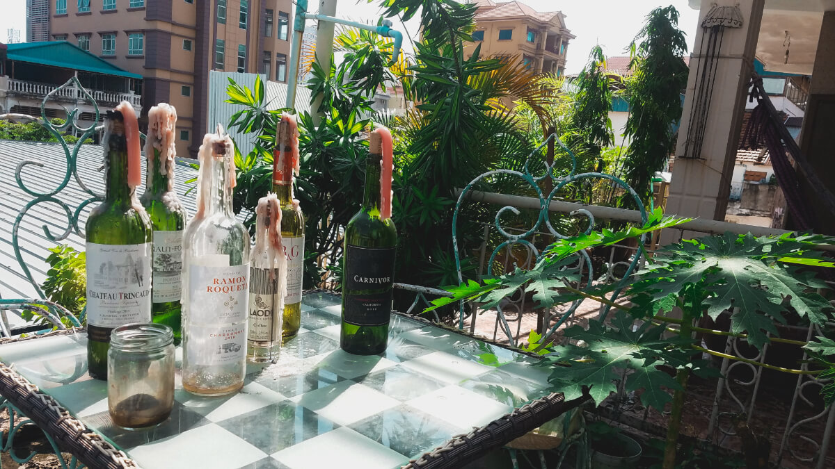 Old wine bottles with dripping wax sit as candle holders on the tabletop of my Cambodia apartment